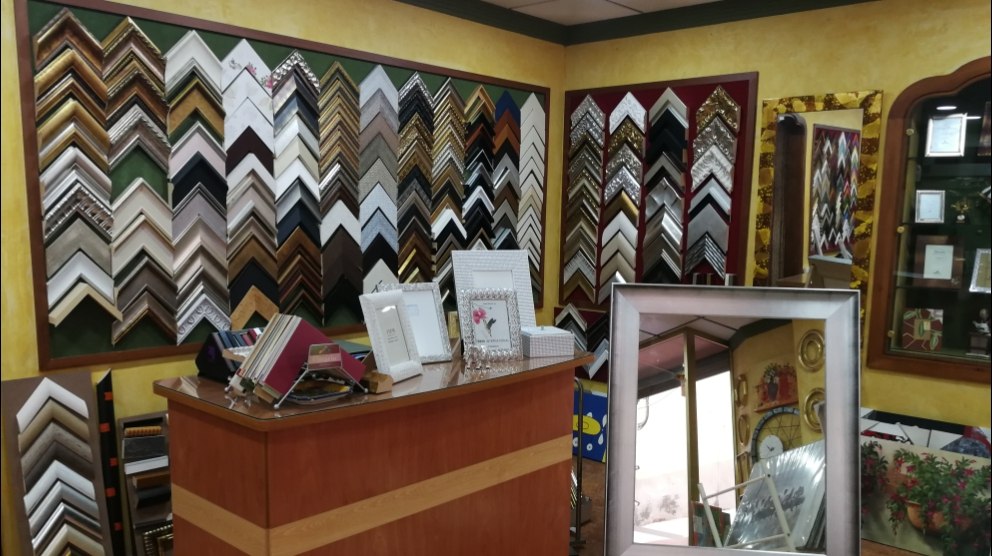 Mostrador de la tienda con muestrarios de passe-partout delante de la pared de molduras.